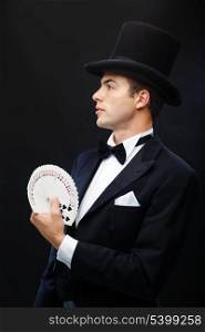 magic, performance, circus, gambling, casino, poker, show concept - magician in top hat showing trick with playing cards