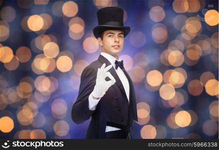 magic, performance, circus, people and show concept - magician in top hat showing ok hand sign over nigh lights background