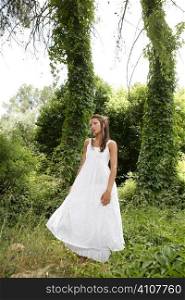 Magic woman in the green forest, long white dress, daytime