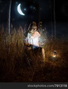 Magical photo of beautiful woman sitting at night forest and reading fairy tale book