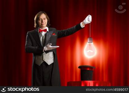 Magician in hat. Image of man magician showing trick against color background