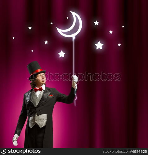 Magician in hat. Image of man magician with balloon against color background