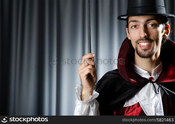 Magician in the dark room with wand
