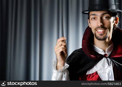Magician in the dark room with wand