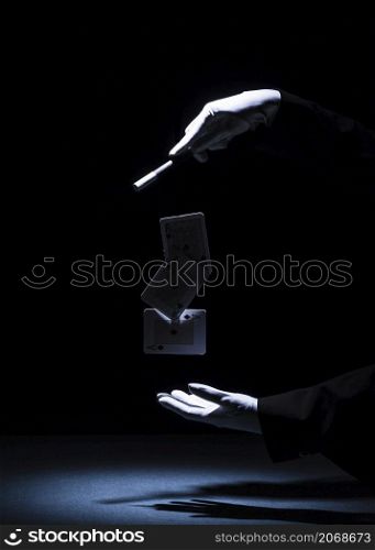 magician performing trick with magic wand against black background