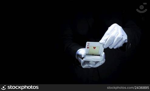 magician performing trick with playing cards against black background