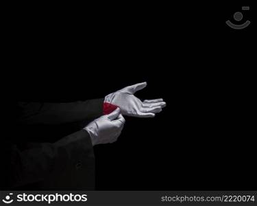 magician s hand removing red napkin from sleeve against black background