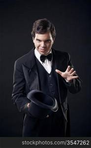 magician showing tricks with top hat isolated on dark background