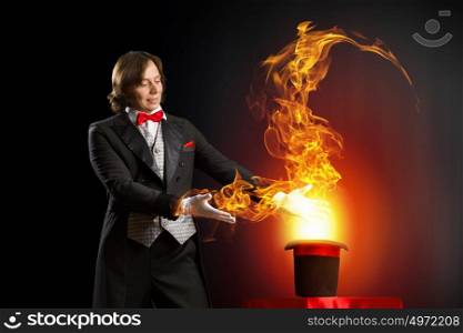 Magician with hat. Image of magician holding hat with fire flames and fumes going out