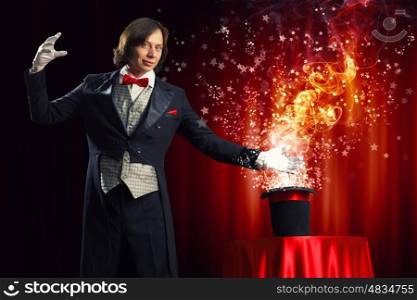 Magician with hat. Image of magician holding hat with lights and fumes going out