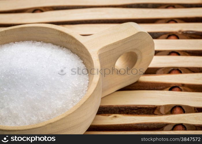 Magnesium sulfate (Epsom salts) in a rustic wooden scoop - relaxing bath concept