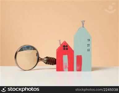magnifier and wooden house on a brown background. Real estate rental, purchase and sale concept. Realtor services, building repair and maintenance
