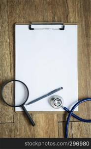 Magnifier with stethoscope on blank notebook on table. Medical background concept.