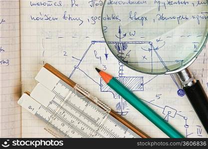 magnifying glass and a slide rule on the old page with the calculations in mechanics