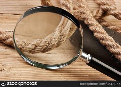 magnifying glass and rope on a wooden background