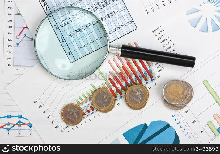 magnifying glass and the working paper with coinss