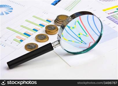 magnifying glass and the working paper with coinss