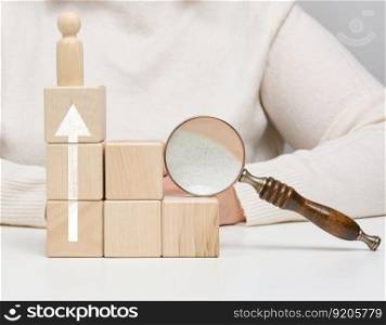 Magnifying glass and wooden men on a white table. Personnel recruitment concept, talented employees. Career advancement