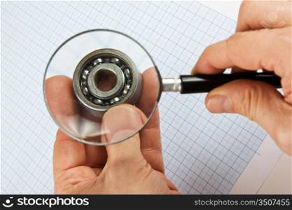magnifying glass in hand and bearing on graph paper