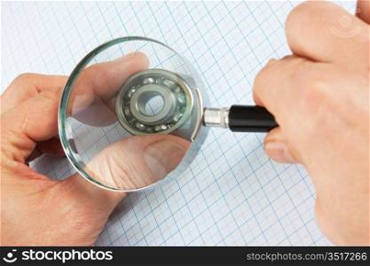 magnifying glass in hand and bearing on graph paper