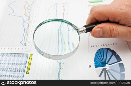 magnifying glass in hand and working paper chart