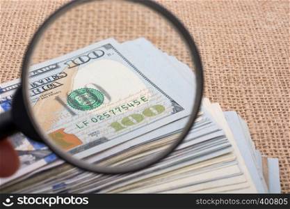 Magnifying glass is held over the banknote bundle of US dollar