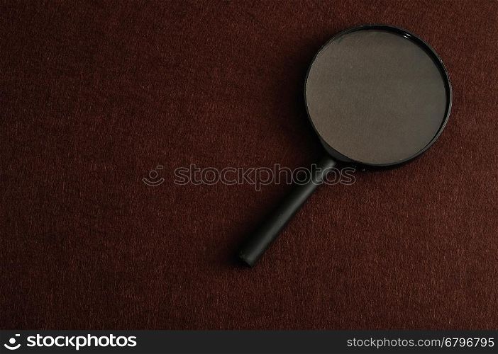 Magnifying glass isolated on a brown background