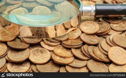 magnifying glass on a heap of coins