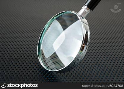 Magnifying glass on a metallic background with perforation of round holes