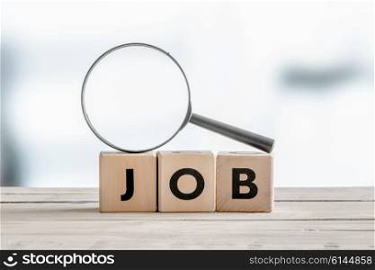 Magnifying glass on the word job on a wooden table