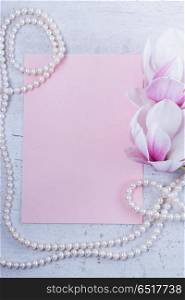 Magnolia flowers flat lay scene. Magnolia flowers and jewellery flat lay composition with copy space on pink paper background