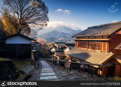 Magome juku downhill in Nakasendo with central alps mountain at sunrise, Kiso valley, Nakatsugawa, Gifu, Japan. Famous travel landmark of preserved Japanese town with Wooden Building Facade in spring
