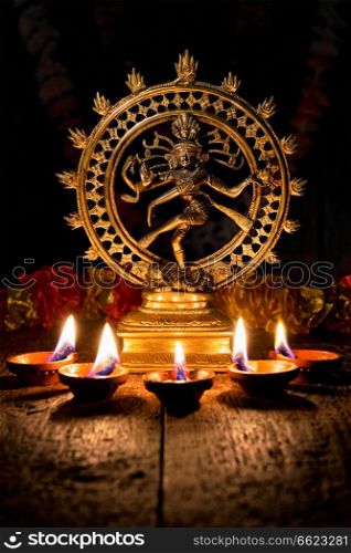 Maha Shivaratri or Diwali concept - Shiva Nataraja figurine with Diwali lights oil ghee candles, India. Shiva Nataraja with Diwali lights