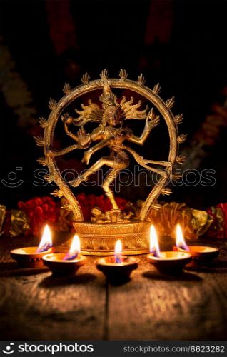 Maha Shivaratri or Diwali concept - Shiva Nataraja figurine with Diwali lights oil ghee candles,  India. Shiva Nataraja with Diwali lights