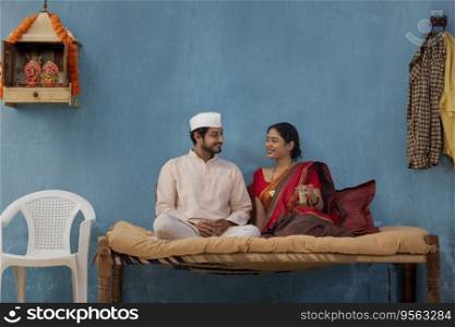 Maharashtrian couple having tea while sitting on cot at home