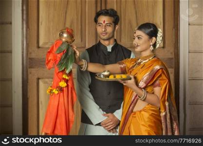 Maharashtrian couple in traditional dress celebrating gudi padwa festival holding a pooja plate.