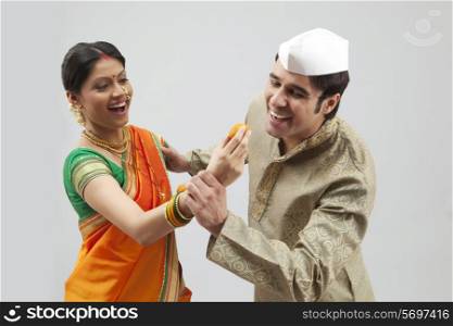 Maharashtrian man trying to eat a laddoo from a woman&rsquo;s hand