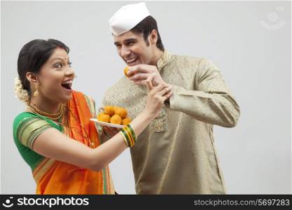 Maharashtrian man trying to feed woman a laddoo