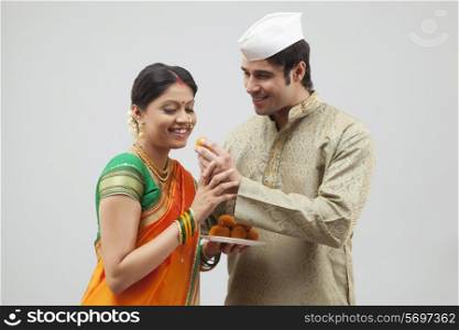 Maharashtrian woman about to eat laddoo from man&rsquo;s hand