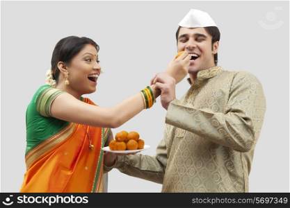 Maharashtrian woman feeding man a laddoo