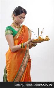 Maharashtrian woman praying while holding a puja thali
