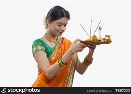 Maharashtrian woman praying while holding a puja thali