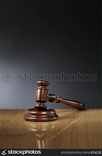 Mahogany wooden gavel on glossy wooden table.