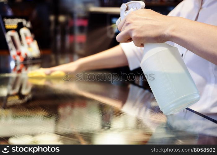 Maid service cleaning glass table with chemicals spray and rag