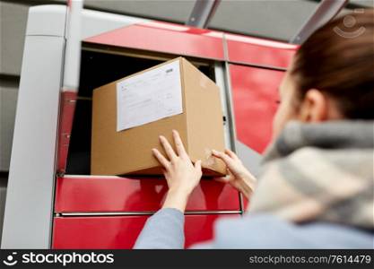 mail delivery and post service concept - woman putting box to automated parcel machine. woman putting box to automated parcel machine