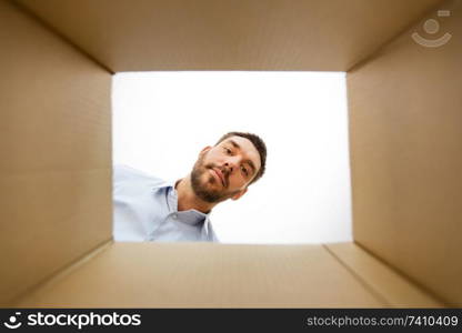 mail delivery and surprise concept - man looking into open parcel box, from below. man looking into open parcel box