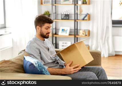 mail delivery, shipment and people concept - disappointed man opening parcel box at home. disappointed man opening parcel box at home
