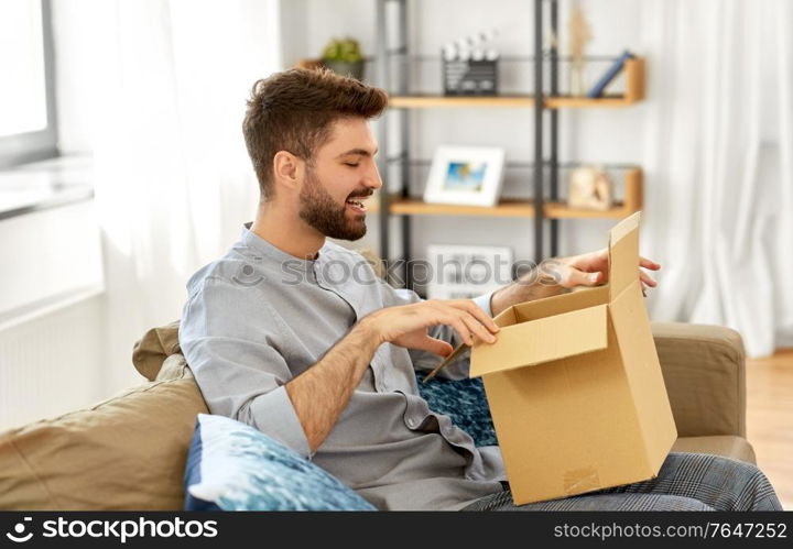 mail delivery, shipment and people concept - happy man opening parcel box at home. happy man opening parcel box at home
