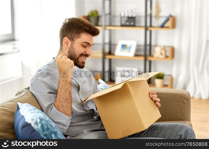 mail delivery, shipment and people concept - happy man opening parcel box at home. happy man opening parcel box at home