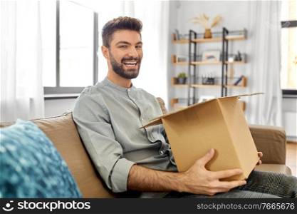 mail delivery, shipment and people concept - happy smiling man opening parcel box at home. happy smiling man opening parcel box at home